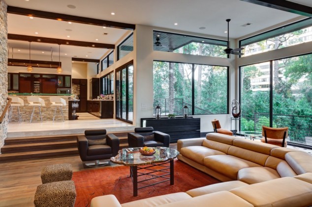 18 Eye Catching Living Room Designs That Will Make You Say Wow cozy modern living with leather sectional and black armchairs also ottoman and coffee table with area rug plus wood floor and area rug with transom windows 915x609 634x422 18 Eye Catching Living Room Designs That Will Make You Say Wow