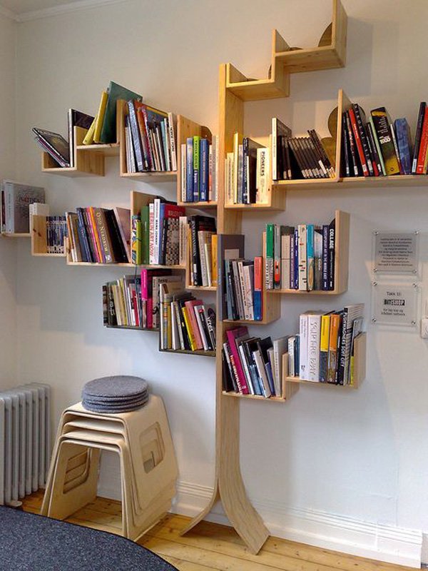 plenty of books organized in tree shaped bookcase a pile of plastic chairs Cool and Modern Tree Shaped Bookshelves You Must See Today